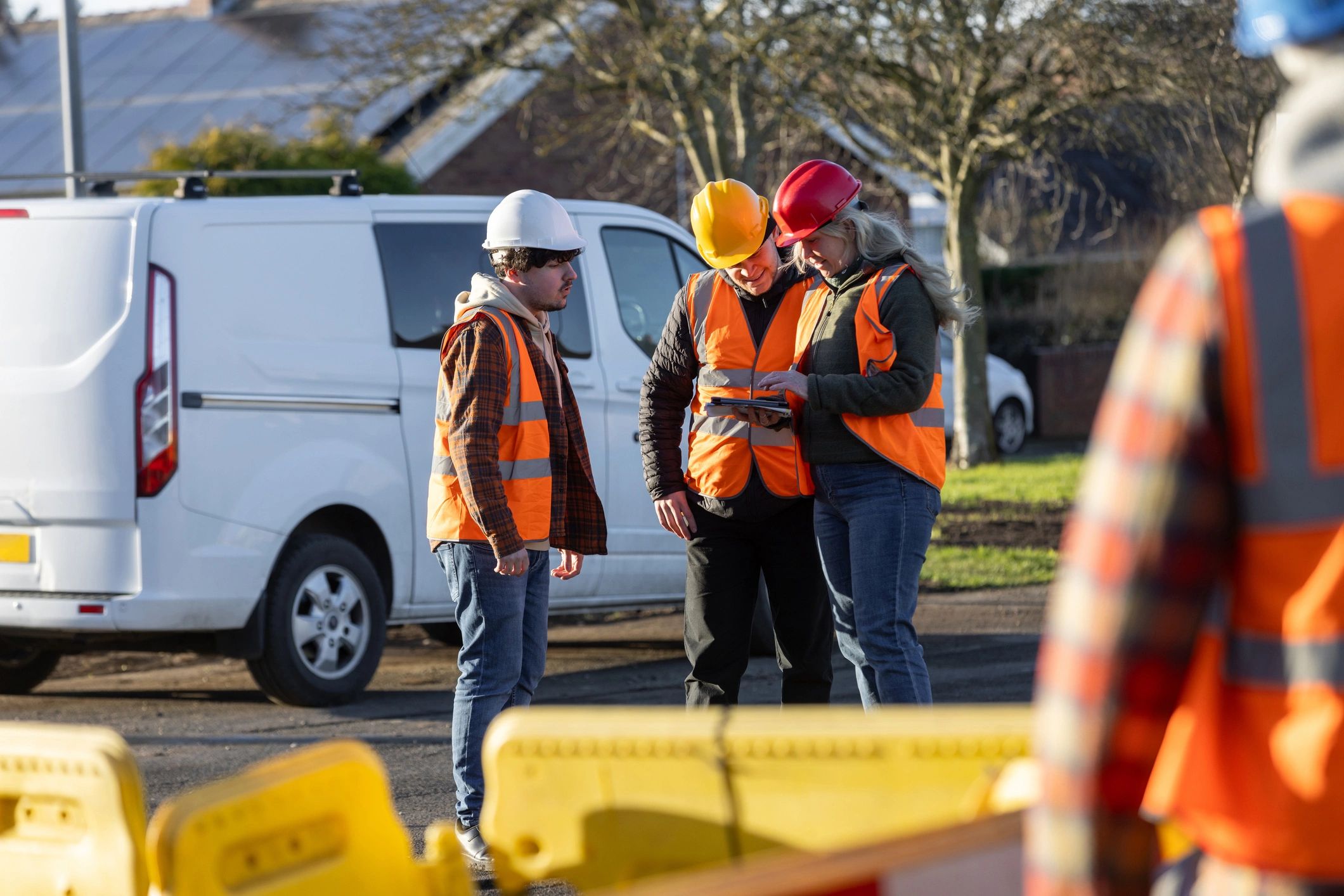 Workers in safety gear discussing plans at a job site
